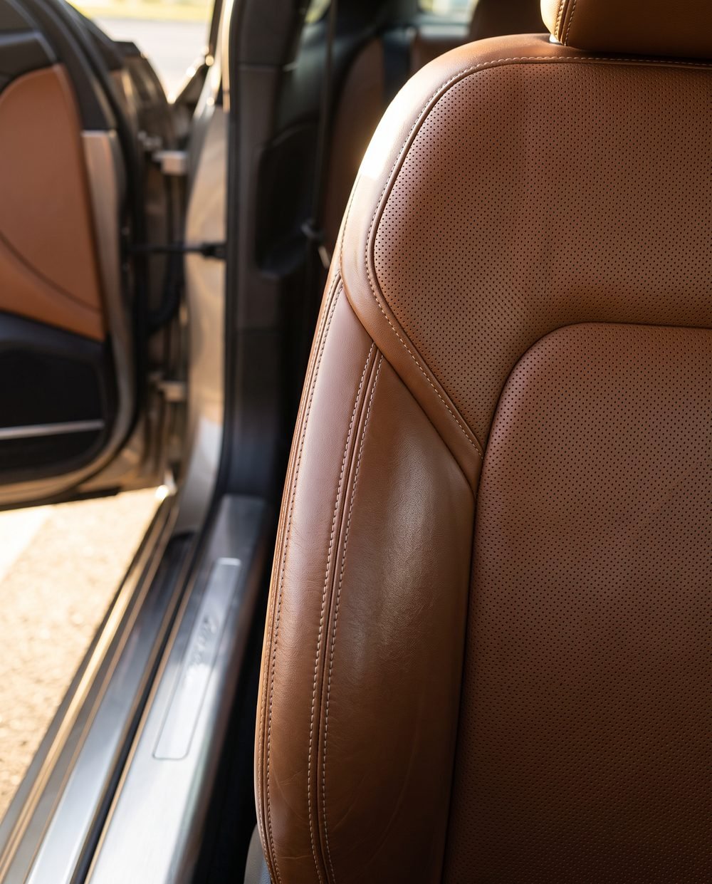 A close view of a cleaned leather seat and stitched trim inside an SUV.